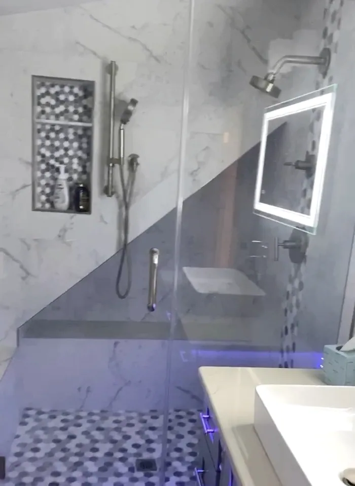 A remodeled bathroom with marble-look tile and a glass shower
