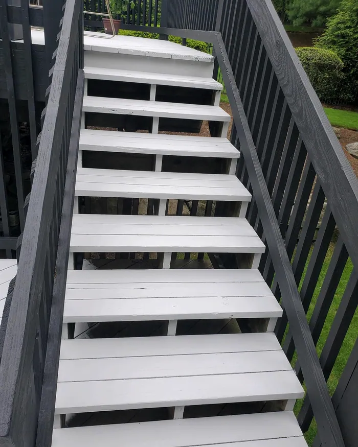 Power-washed and stained deck stairs with a black railing