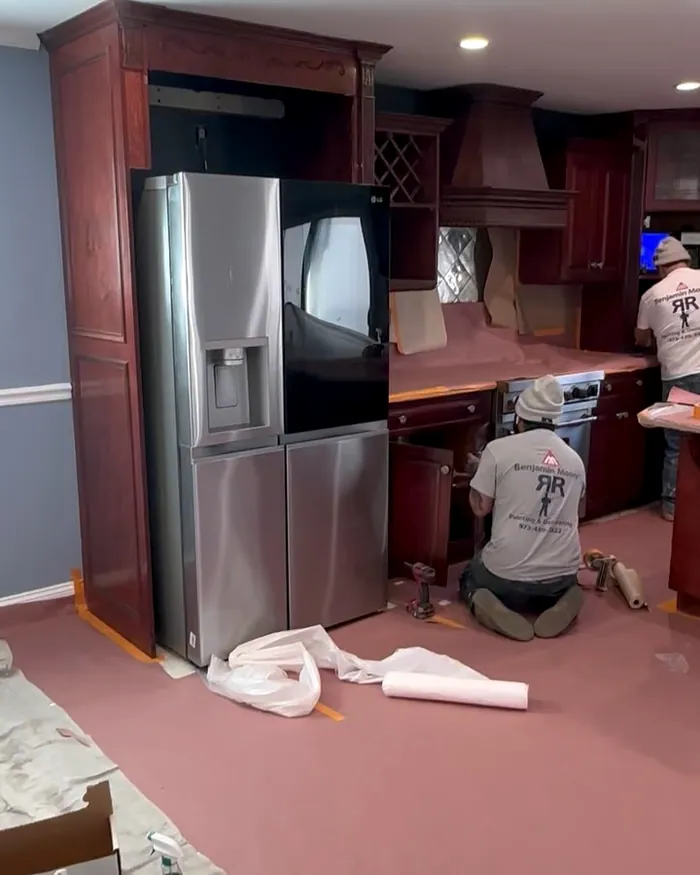 RR crew in branded shirts prepping kitchen cabinets for paint