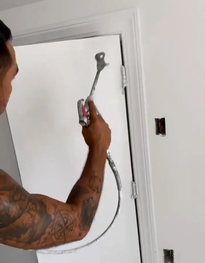 A painter spraying a door white