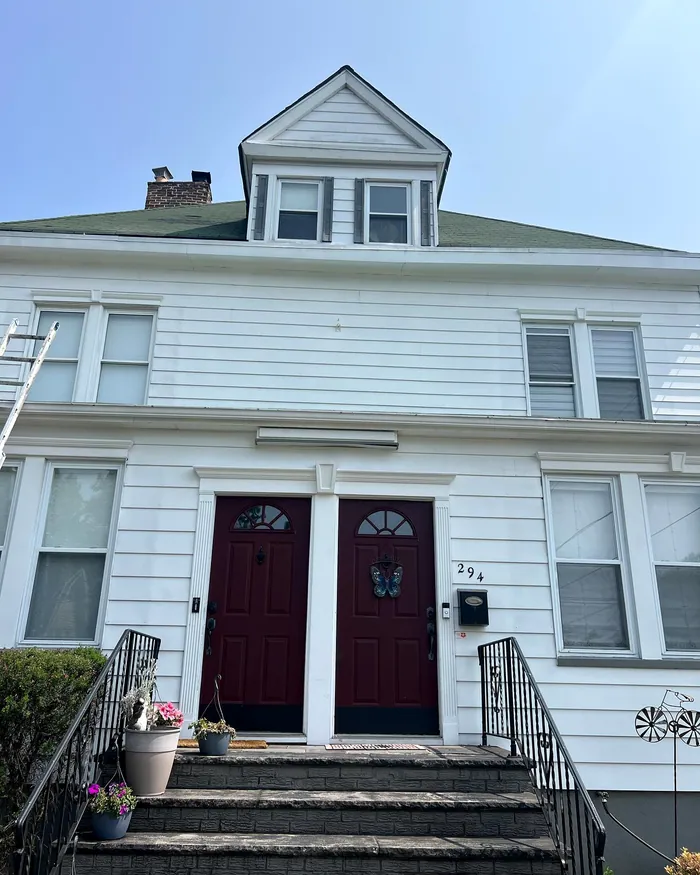 Two-family exterior: Clapboard, trim and two red doors.